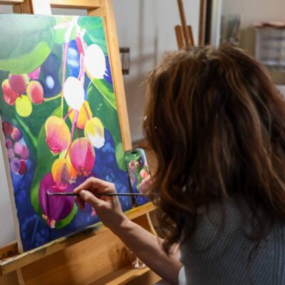 A Brandi Dayton Art student painting a floral scene on an easel.