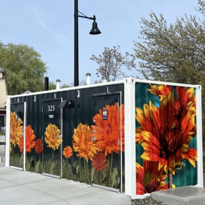 Stylized images of Heliopsis False Sunflowers and Gaillardia Blanket Flowers sweep across the front and one end of a shipping container art wrap at Columbia Gardens.