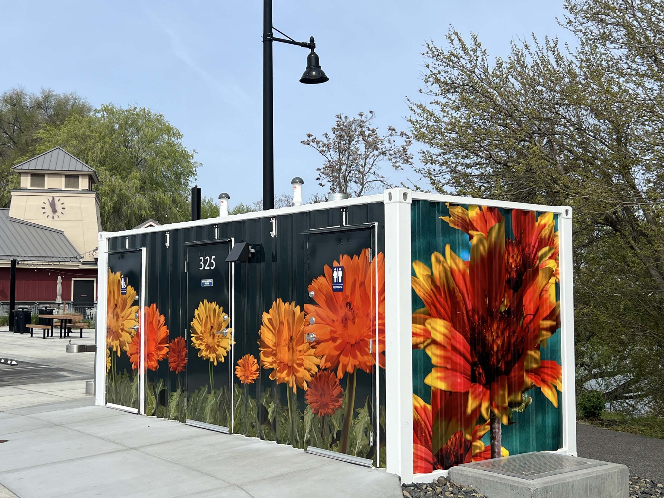 Stylized images of Heliopsis False Sunflowers and Gaillardia Blanket Flowers sweep across the front and one end of a shipping container art wrap at Columbia Gardens.