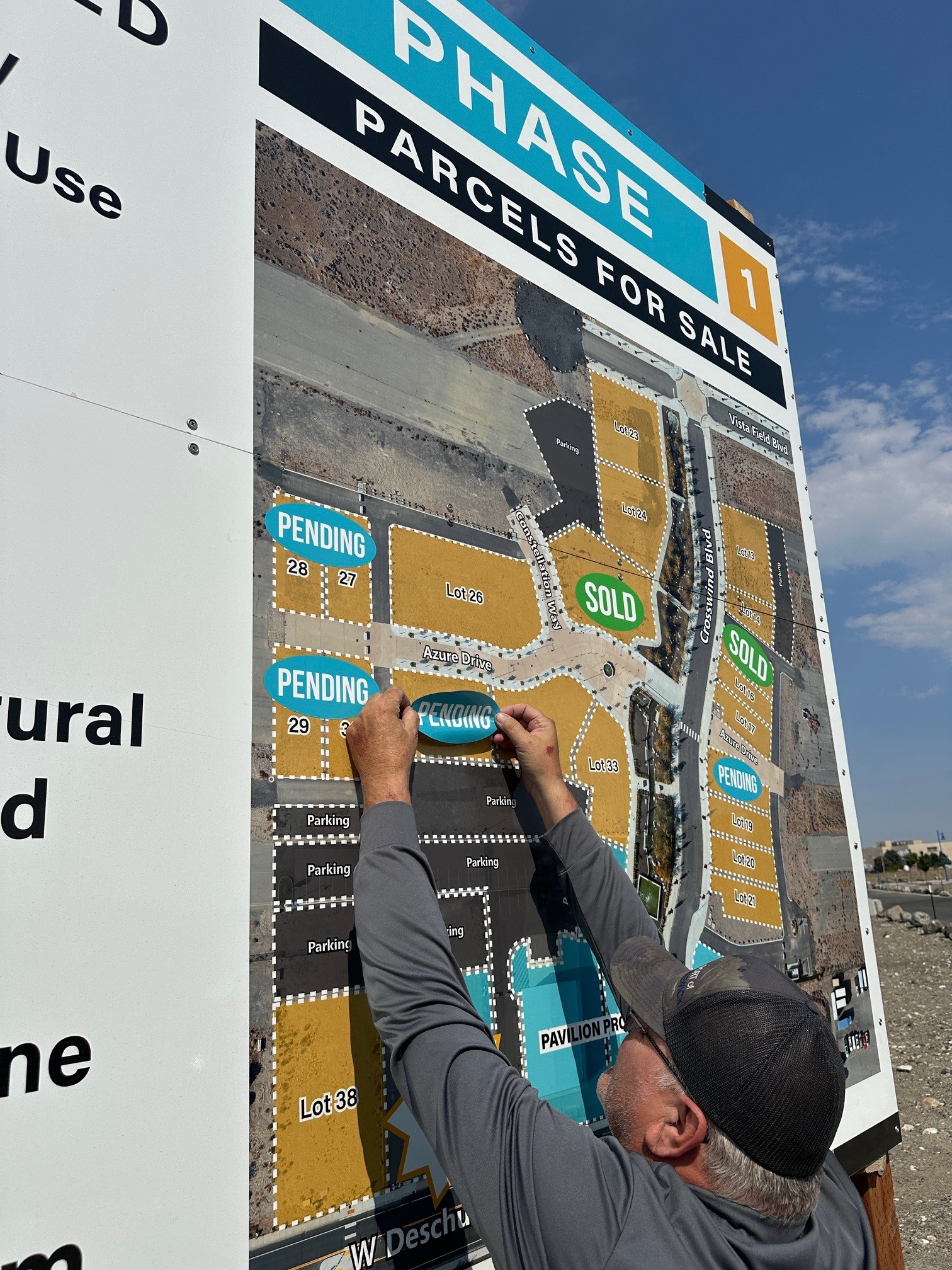A Port team member adds a sticker to Lot 31 on the Vista Field phase 1 billboard, marking it as a pending sale.